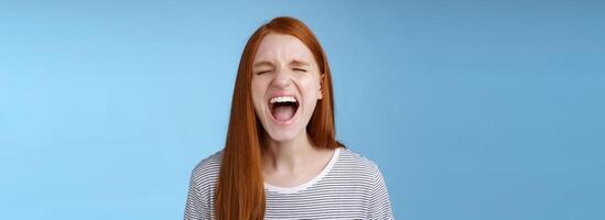 Girl screaming out loud showing attitude take out stress being fed up complaining hursh life shouting closed eyes yelling pissed standing bothered distressed blue background photo