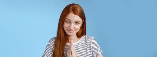 Cute girl acting kind angel gazing camera silly smiling asking please help press palms together pray glancing flirty begging favour standing blue background pleading sincere lend clothes photo