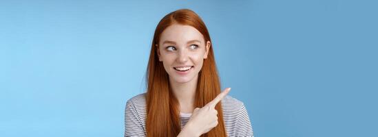 Intrigued good-looking redhead joyful curious girl watching looking upper left corner interested smiling broadly visit cool amusing place explore travelling new country astonished, blue background photo