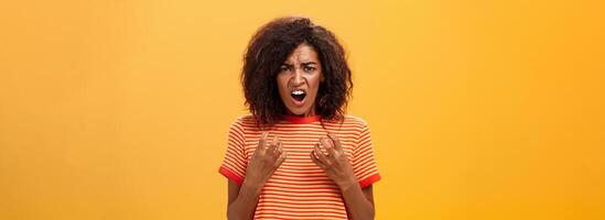 Waist-up shot of woman feeling upset feeling unfair things happened complaining and whining with regret frowning gesturing with palms near breast standing over orange background photo