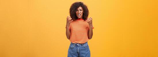 Woman going out of control feeling sick and tired ready to show rage and fury. Portrait of pissed and annoyed furious female clenching raised fists frowning and frimacing looking with scorn and hate photo