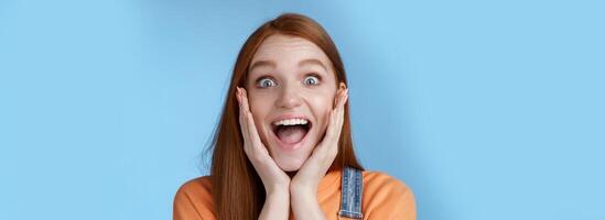 Impressed excited overwhelmed young redhead girlfriend fan screaming thrilled express afection adore awesome music band yelling happily reacting surprised astonished, standing blue background photo