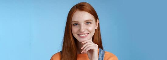 Curious smart creative young female redhead blue eyes have perfect idea how spend summer vacation smiling joyful look intrigued thoughtful touch chin pondering choice, standing blue background photo