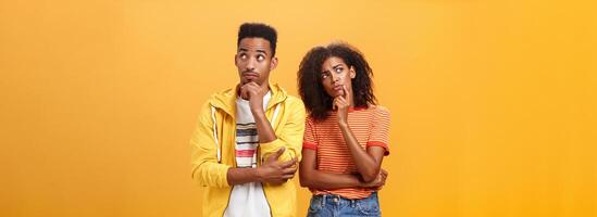 Two brains better than one. Thoughtful couple of african american friends in stylish urban outfit standing in thinker pose looking up determined and focused making up plan how spend evening photo