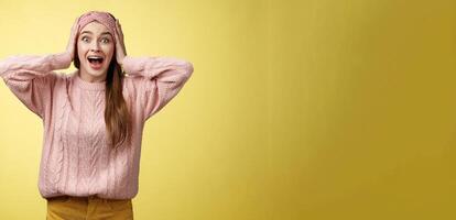 Frustrated girl in panic, screaming grabbing head yelling troubled and scared, staring with buged eyes concerned, feeling nervouse, insecure, shouting frightened and worried against yellow background photo