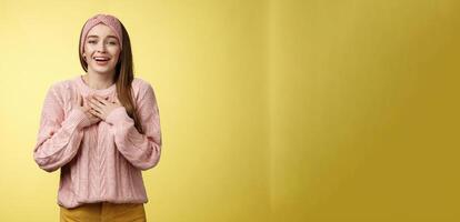 Grateful delighted charming young 20s woman wearing sweater pressing arms to chest happily, thankful, expressing gratitude, heartfelt appreciating gesture smiling amused, in love with romantic gift photo