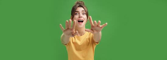 Excited and addicted goog-looking young woman reaching hands forward to camera with reckless look wanting grab something she desire seeing thing she wanted for long time over green background photo