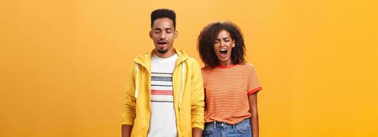 elegante y atractivo hermano y hermana terminado naranja antecedentes bostezando con cerrado ojos y cansado expresión siendo agotado y agotado después relación comercial con casa quehaceres limpieza lío después fiesta foto