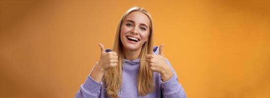 Close-up charming delighted cute female customer give positive feedback show thumbs-up like gesture smiling broadly agree recommend perfect product skincare standing satisfied orange background photo