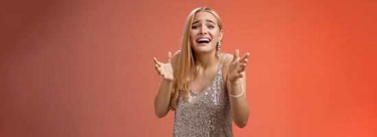 Panicking upset miserable heartbroken blond girl crying raising hands begging not go broke-up boyfriend look sorrow distressed freak-out standing devastated red background during party photo