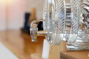 A glass water dispenser jar sits on the counter providing drinking water to coffee shop patrons or hotel restaurant. Soft and selective focus. photo