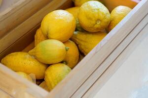 Ripe lemons in a wooden crate. The fruit is round and oval. The young fruit is green When cooked it will be yellow. The fruit flesh is juicy and sour taste. photo