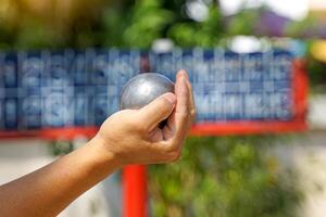 jugadores sostener un petanca pelota en su manos y preparar a lanzar eso en orden a sitio el petanca pelota como cerca a el objetivo pelota como posible. foto