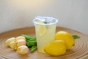 un vaso de limón soda bebida es metido juntos con un limón en un rota mesa. eso es un menú hecho desde limón jugo ese es Rico en vitamina C. eso es beneficioso a salud y ayuda a actualizar. foto