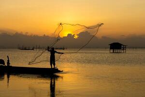 Silhouettes fisherman throwing fishing nets photo