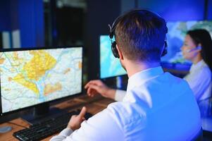 Center of dispatching maintenance. Portrait of cheerful woman and man working via headset microphone while sitting on navigation controller board photo