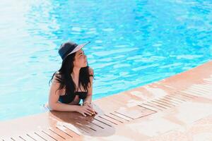 Vacation lifestyle scene of young woman sitting in swimming pool in morning time. Weekend and holiday lifestyle concept photo