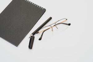 fuente bolígrafo cuaderno y lentes en composición en negro y blanco foto