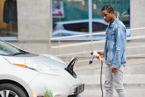 africano americano hombre cargando su eléctrico coche. foto
