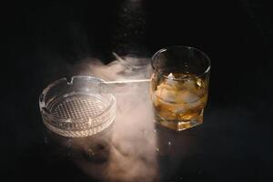 Whiskey drink with smoking cigar photo