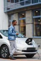africano americano hombre cargando su eléctrico coche. foto