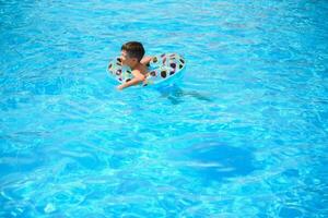 niños verano vacaciones. niño nadando en piscina. niños teniendo divertido a parque acúatico. gracioso chico en inflable caucho círculo. Hora de verano. atracciones concepto foto