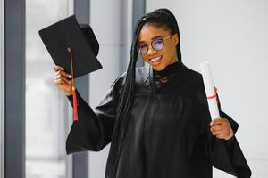 contento africano americano hembra estudiante con diploma a graduación foto