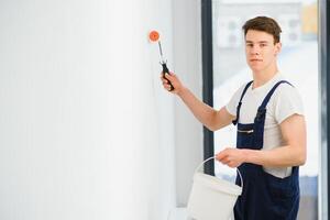 The painter is painting a wall in a room with a roller. photo