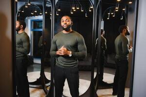 Stylish casual african american man at fitting room clothes store, looking on mirror. The concept of stylish men's clothing. photo