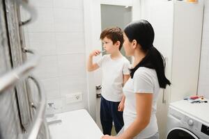 linda madre enseñando niño chico dientes cepillado foto