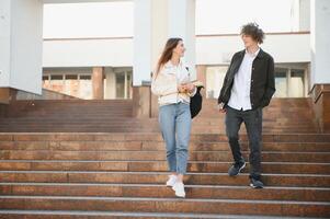 Front view of two students walking and talking in an university campus. photo