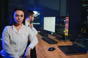 Team of stockbrokers are having a conversation in a dark office with display screens photo