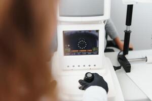 Modern medical equipment. Close up of ophthalmologist using auto refractometer while examining child eyes. photo