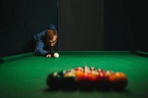 Young handsome man leaning over the table while playing snooker photo