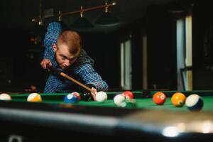 Young man playing billiards in the dark billiard club photo