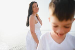 Happy mother and son walk along the ocean beach having great family time on vacation on Pandawa Beach, Bali. Paradise, travel, vacation concept photo