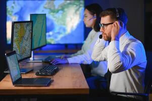 Center of dispatching maintenance. Portrait of cheerful woman and man working via headset microphone while sitting on navigation controller board photo