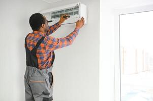 Young African Male Technician Repairing Air Conditioner photo