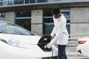 African American man charging his electric car. photo