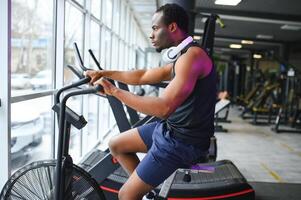 Attractive man at health club, exercising on bike photo