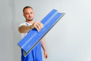 A man processes the wall with a spatula. Plasterer at work. photo