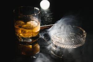 Whiskey drink with smoking cigar photo