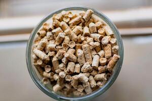 Pellet for stove or boiler in a glass, compressed wood granule photo