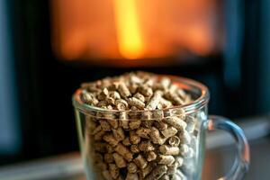 Pellet for stove or boiler in a glass, compressed wood pellet with a stove in background photo