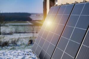 Solar panels with snow on ground on a well-exposed wall of an individual house, making savings following the energy crisis, eco-citizen gesture, green energy photo