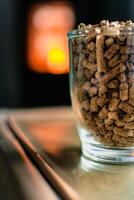 Pellet for stove or boiler in a glass, compressed wood pellet with a stove in background photo