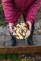 Person who put in a composter some kitchen waste like vegetables, fruits, eggshell, coffee grounds in order to sort and make bio fertilizer photo