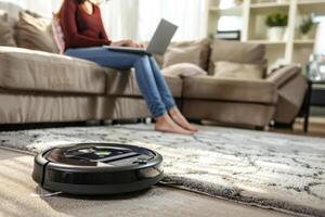 AI generated Robotic vacuum cleaner cleaning the living room while woman working with laptop on sofa at home. Generative AI photo