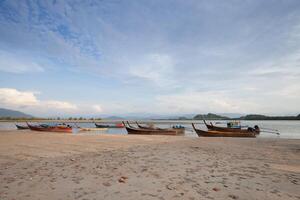 Long tail boat on tropical beach, under cloudy sky photo