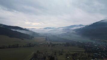 antenne visie van mistig en bewolkt dorp in vallei in Slowakije video